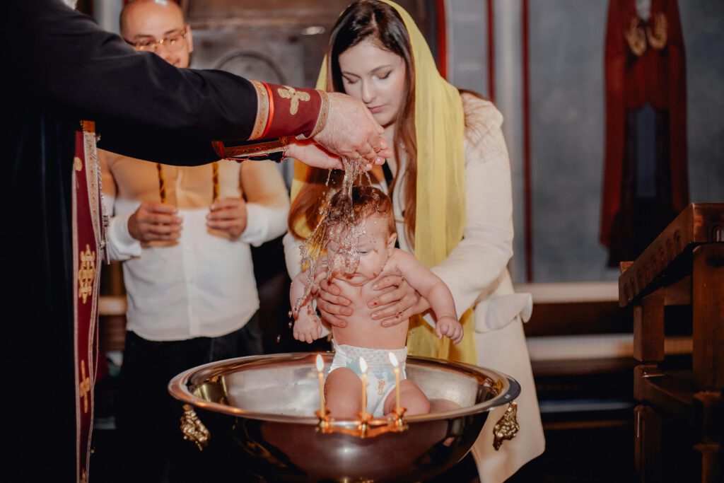 A traditional baby baptism ceremony inside a church with priest and family present.