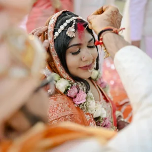 Bride receiving sindoor in a vibrant Indian wedding ceremony.