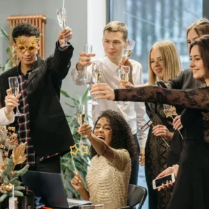 Group of diverse adults enjoying a festive office party, raising a toast in celebration.